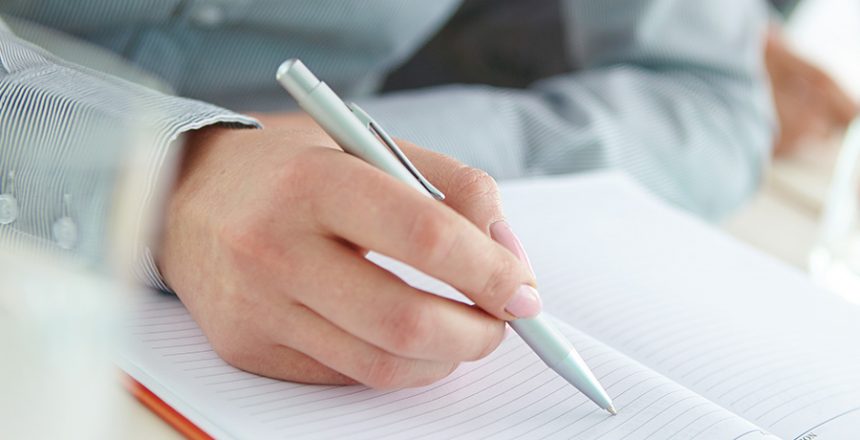 Businesswoman hand holding pen over empty notebook page