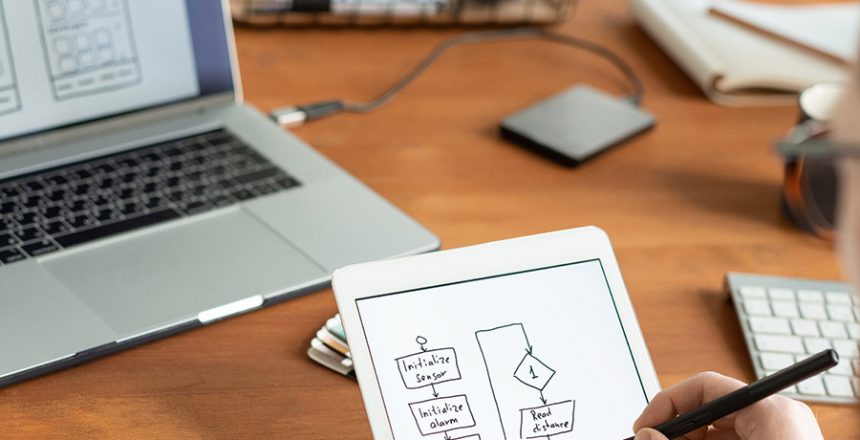 Over shoulder view of man using digital tablet and stylus and drawing scheme for ui design